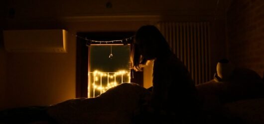 a person sitting on a bed in a dark room